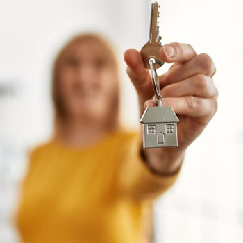 Main tenant une clé de maison, symbole de propriété et d'accession à la propriété