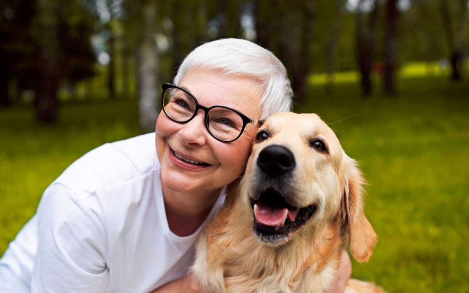 Une femme âgée souriante partageant un moment de bonheur avec son fidèle compagnon canin.