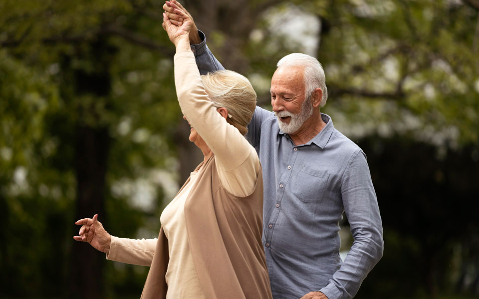 Couple de personnes âgées dansant joyeusement dans un parc