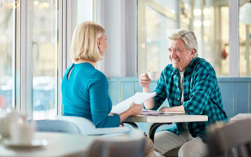 Deux seniors partagent un café autour d'une table avec des papiers